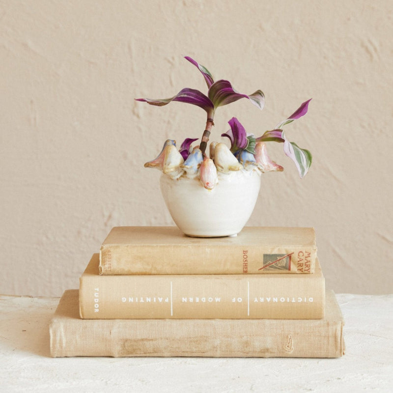 Small potted plant on top of stacked books against a beige wall