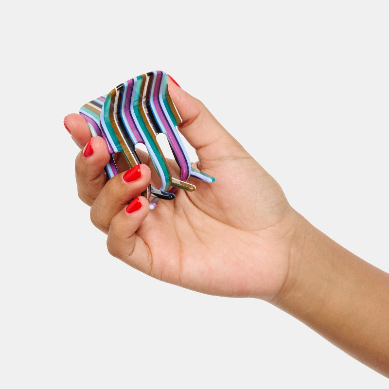 Hand holding Chunks Ursa Hair Claw Clip in Frances on a white background