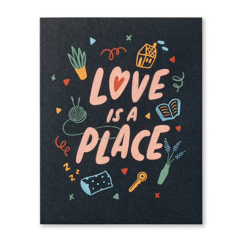 New Home Greeting Card - Love is a Place. Illustration shows typography surrounded by drawings of home related items on a dark black background. Some of the items include a house, a potted houseplant, a house key, a vase of flowers, a book, a ball of knitting yarn, a pillow, and more.