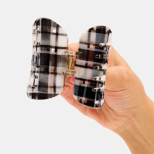 Hand holding the Chunks Juno Hair Claw Clip in black and white plaid open on a white background
