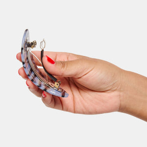 Hand holding Oval Hair Barrette in Phantom open on white background
