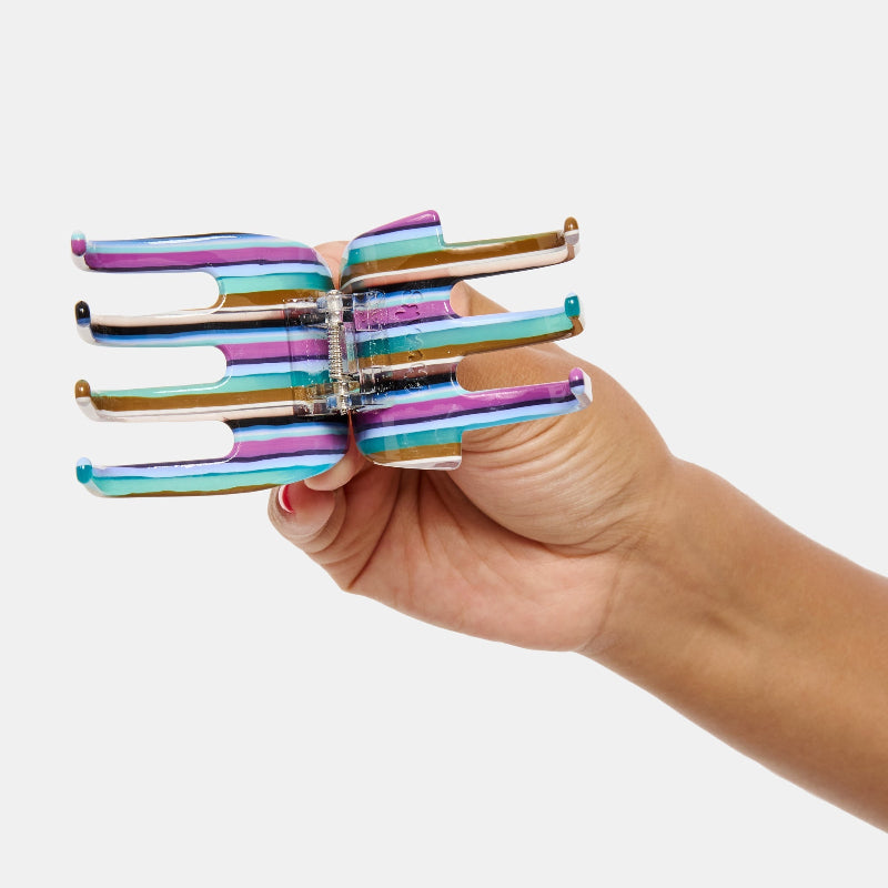 Hand holding Chunks Ursa Hair Claw in Frances open on a white background