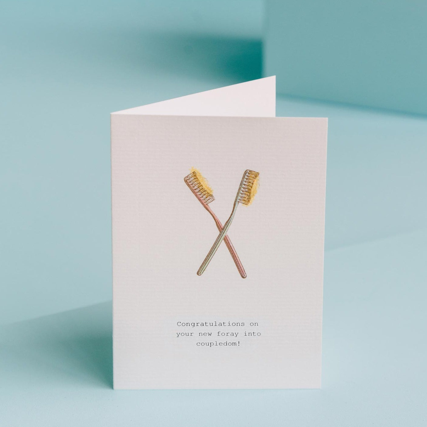 Card reads: "Congratulations on your new foray into coupledom!" The card pictures two glittery toothbrush illustrations.